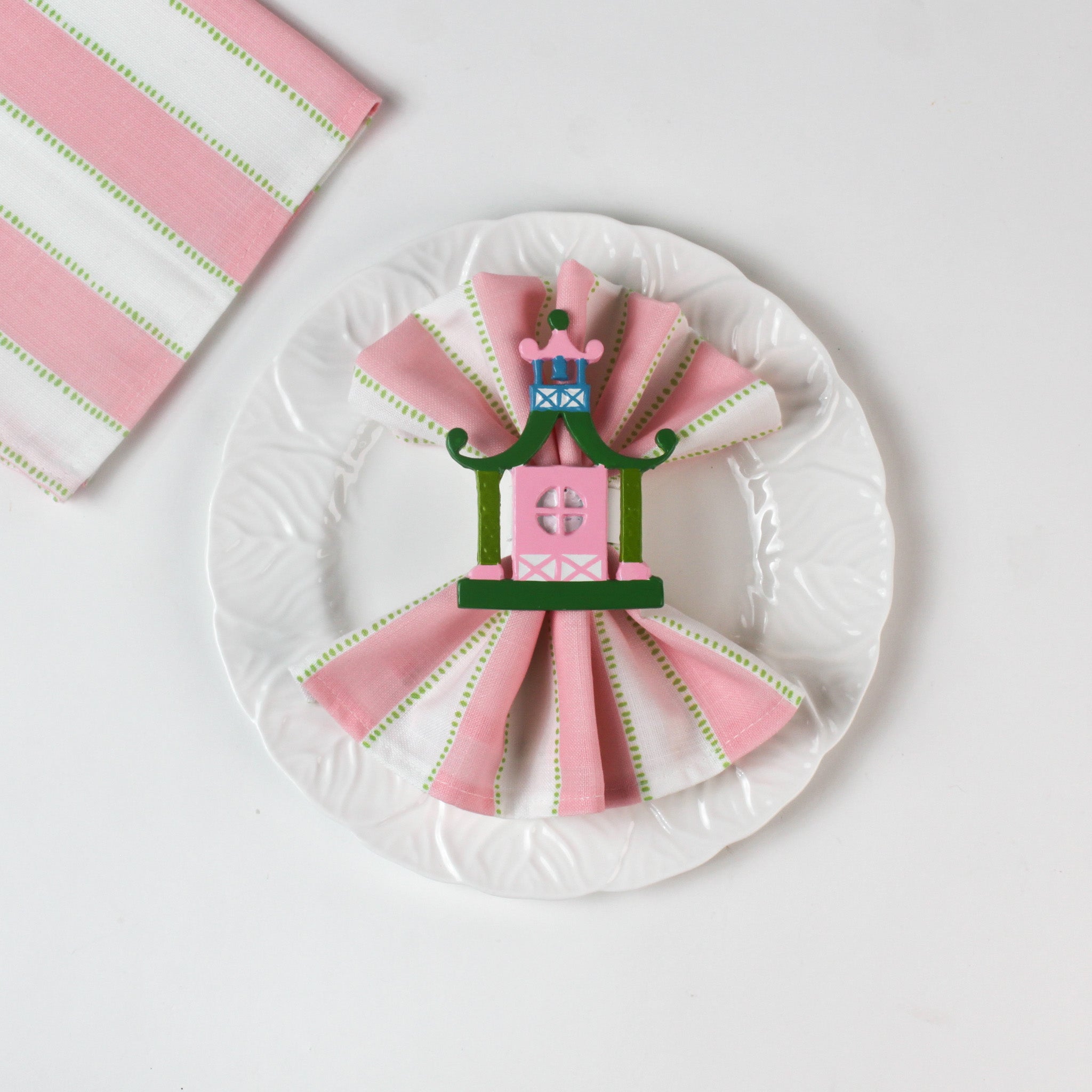 Chinoiserie Pagoda Painted-Metal Napkin Rings with one on a green, pink and white white dinner napkin