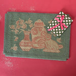 A small pink and green rug with chinoiserie motifs.