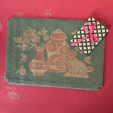 A small pink and green rug with chinoiserie motifs.