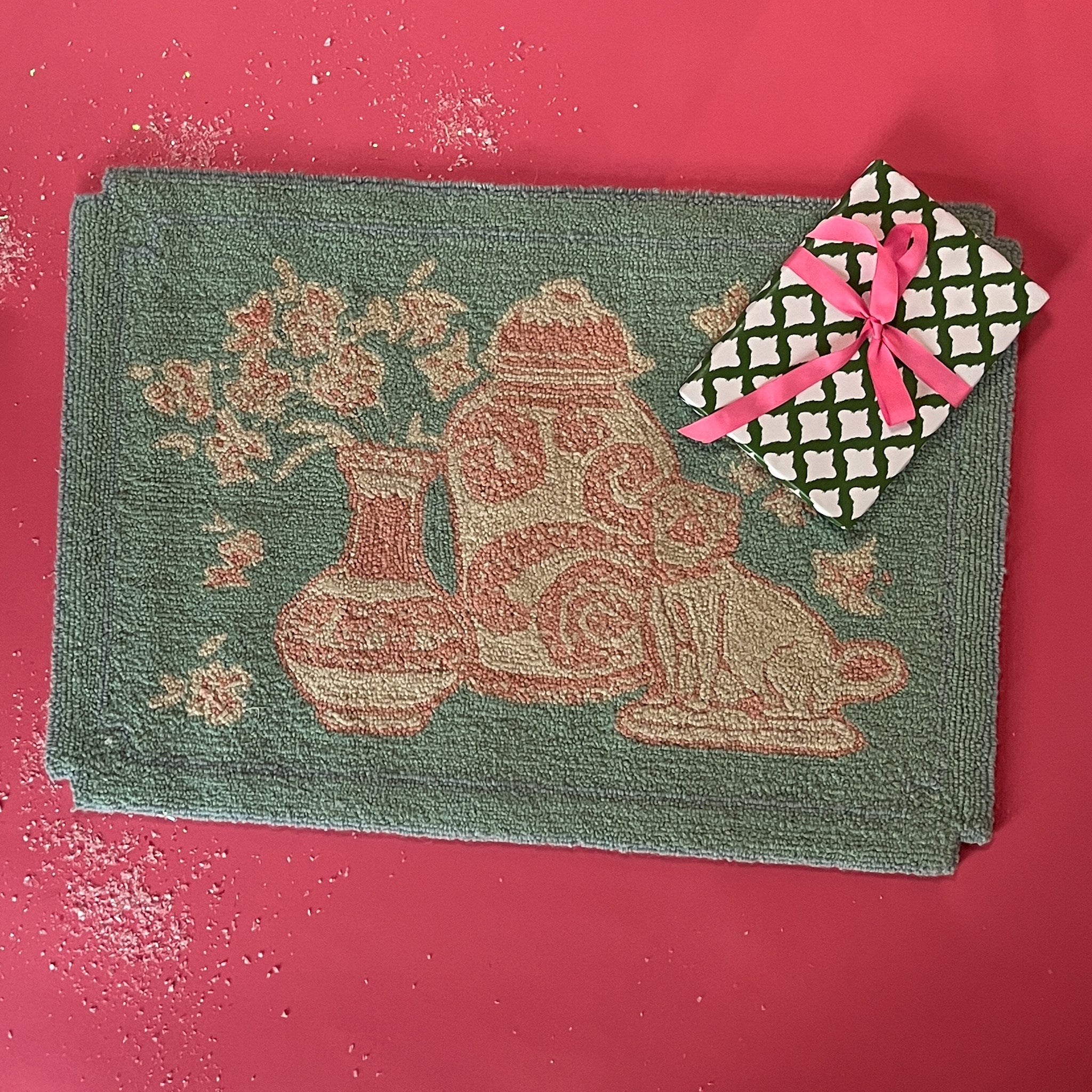 A small pink and green rug with chinoiserie motifs.