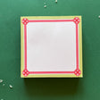 square notepad with red decorative borders, displayed on a green background
