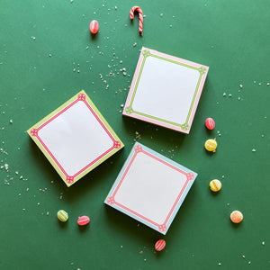 Colorful square notepads with decorative borders, displayed on a green background surrounded by candy canes and decorative balls.