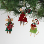 Three festive felt mouse ornaments wear holiday outfits—one holds a gingerbread cookie, another a giant lollipop, and the third a Christmas pudding. all three hanging in a pine branch