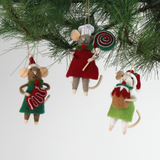 Three festive felt mouse ornaments wear holiday outfits—one holds a gingerbread cookie, another a giant lollipop, and the third a Christmas pudding. all three hanging in a pine branch