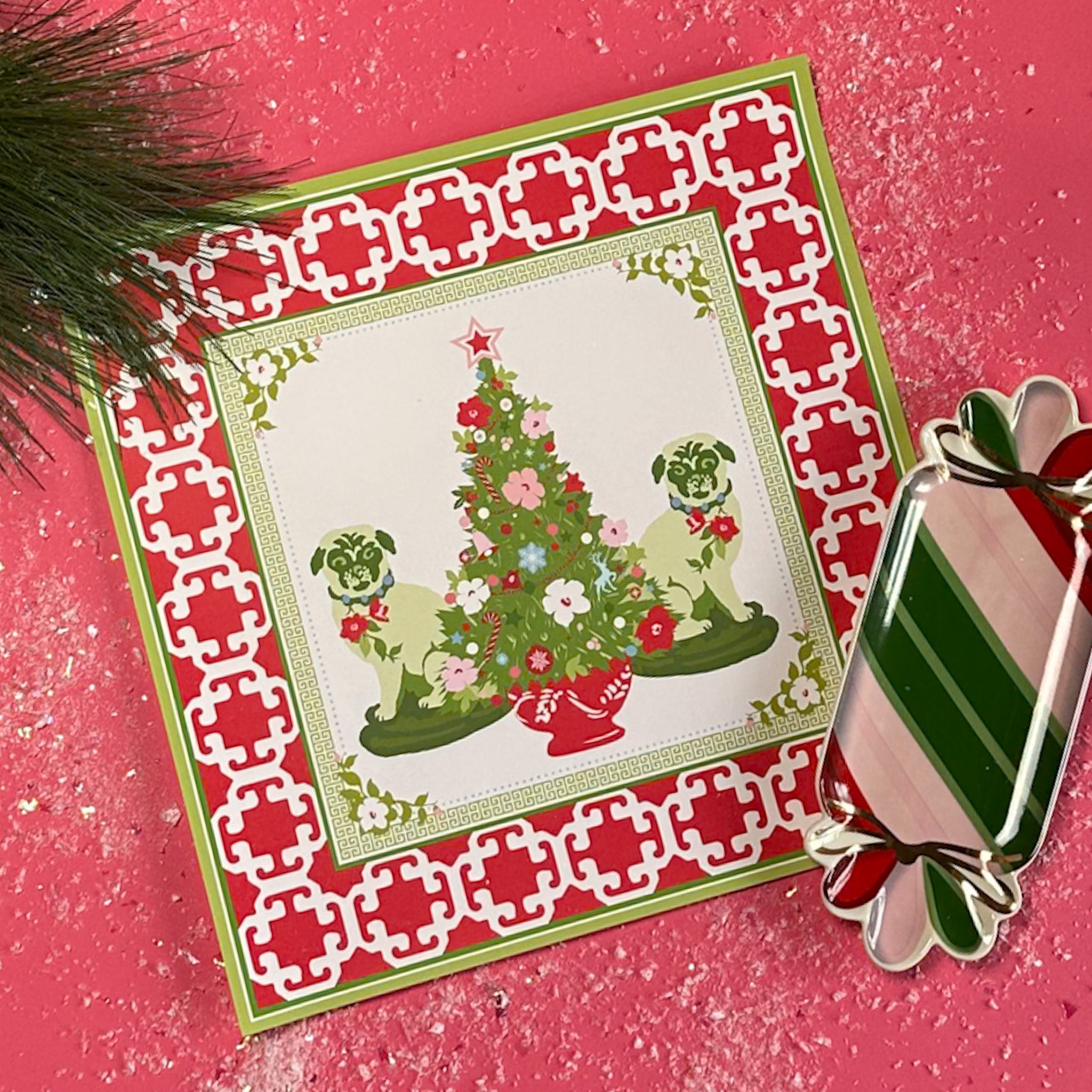Christmas Pugs Square Paper Placemats in a red surface with a candy striped plate on the side