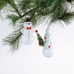 Two snowman ornaments hanging on a Christmas tree branch.