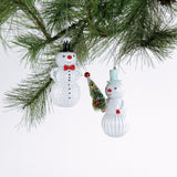 Two snowman ornaments hanging on a Christmas tree branch.