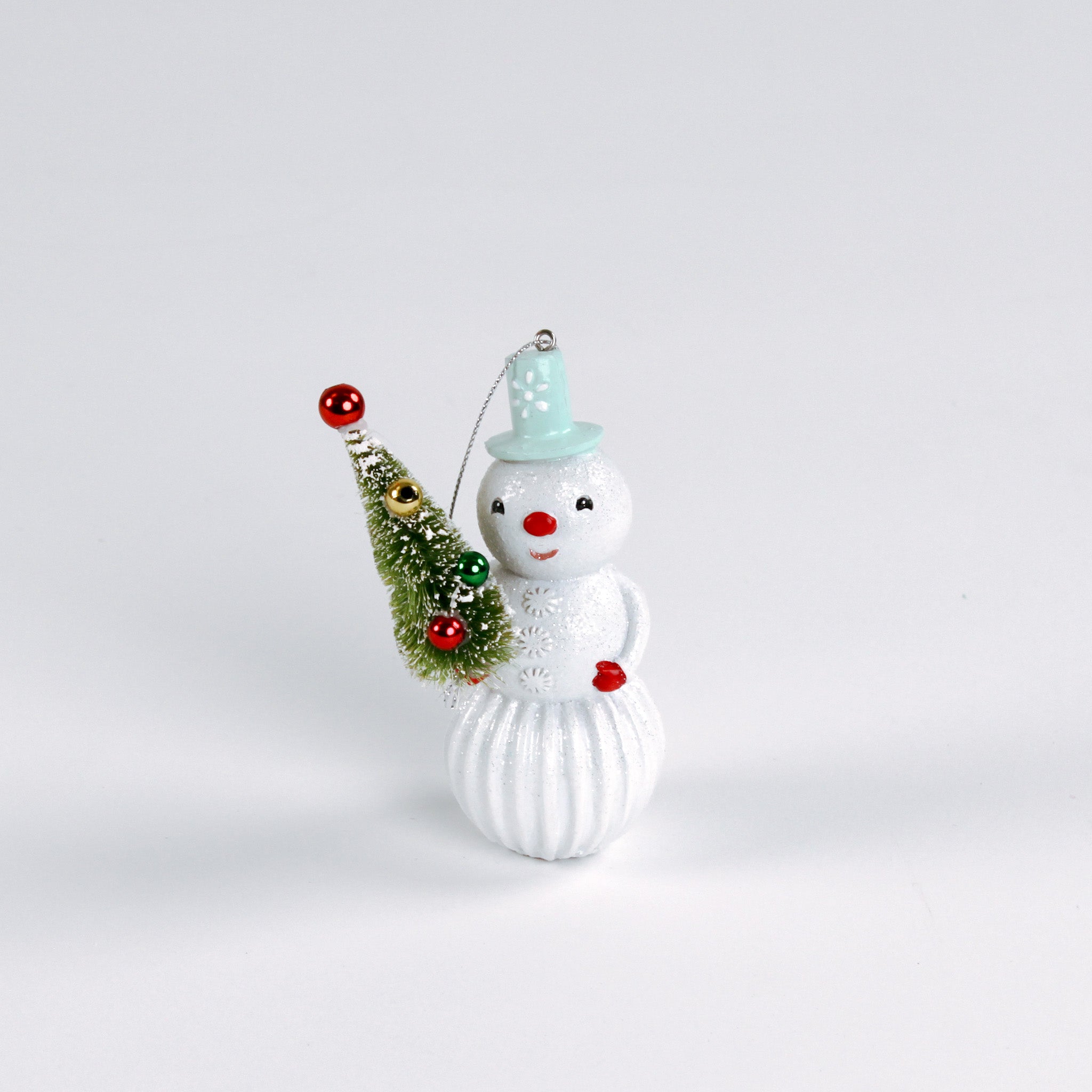 Decorative snowman ornament with a small tree on a white background