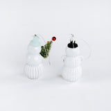 Two white glass snowman ornaments on a white background