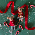 Set of two Mice in pajamas Christmas Ornaments laid on a green surface with a red ribbon and candy canes