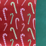 colorful christmas wrapping paper with colored candy cane motifs on a red background.