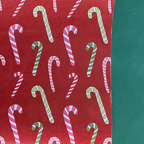 colorful christmas wrapping paper with colored candy cane motifs on a red background. 