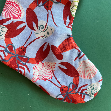 A close up of a lobster print red and blue Christmas stocking. 