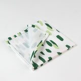 Close-up of folded cloth napkin with a green brushstroke pattern on white fabric.