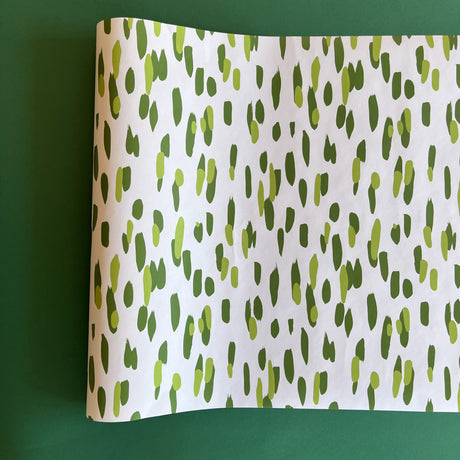 A roll of wrapping paper in painterly patterns and green in color.