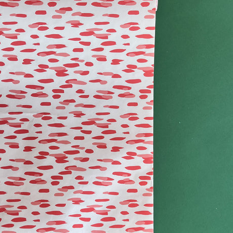 A roll of wrapping paper in painterly patterns and pink in color.