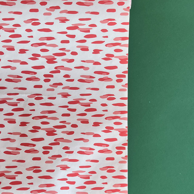 A roll of wrapping paper in painterly patterns and pink in color.