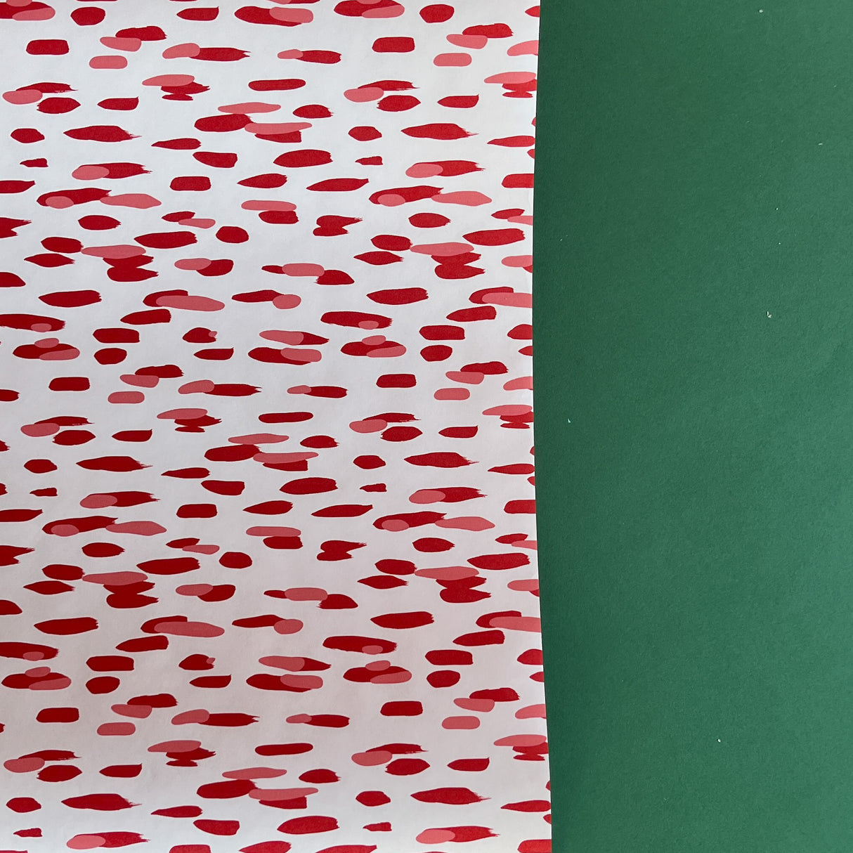A roll of wrapping paper in painterly patterns and red in color.