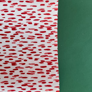 A roll of wrapping paper in painterly patterns and red in color.