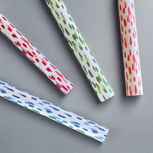 Four rolls of wrapping paper in painterly patterns and different colors.