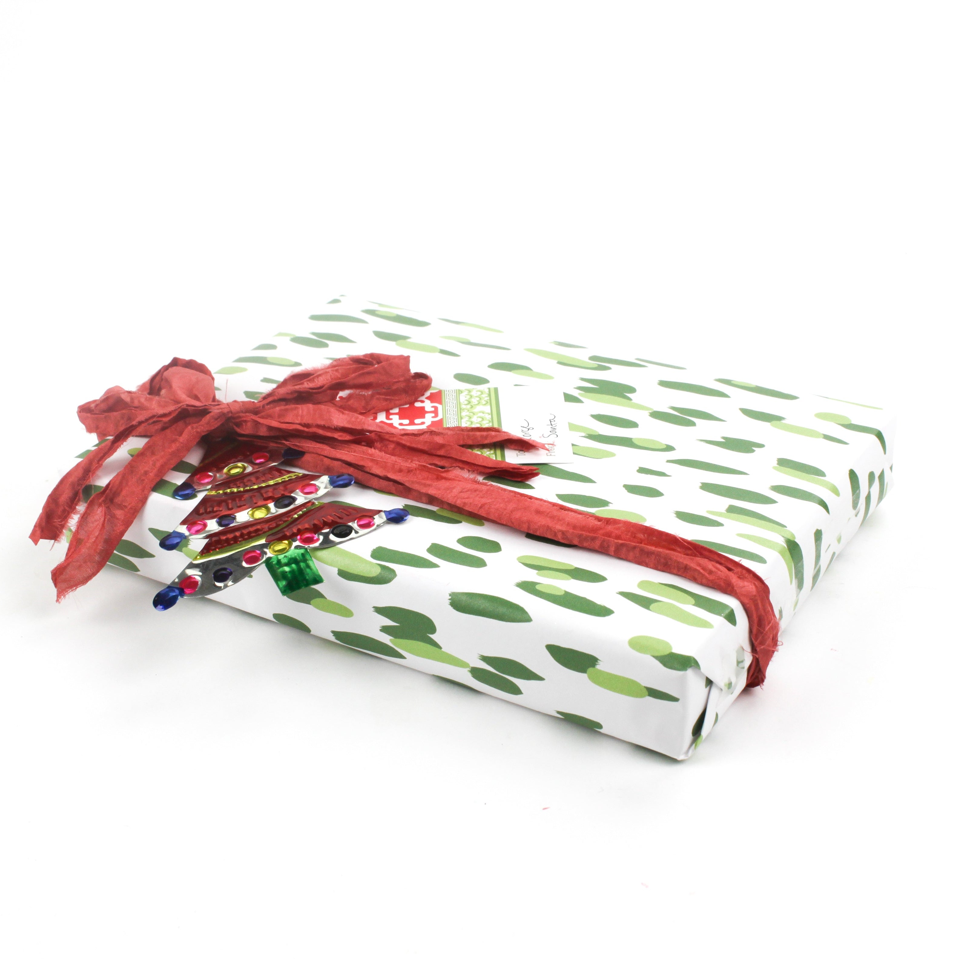 Side view of gift wrapped in green brushstroke wrapping paper with red ribbon.