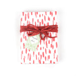 Front view of gift wrapped in pink brushstroke wrapping paper with red ribbon and gift tag.