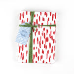 Front view of gift wrapped in red brushstroke wrapping paper with green ribbon and blue gift tag.