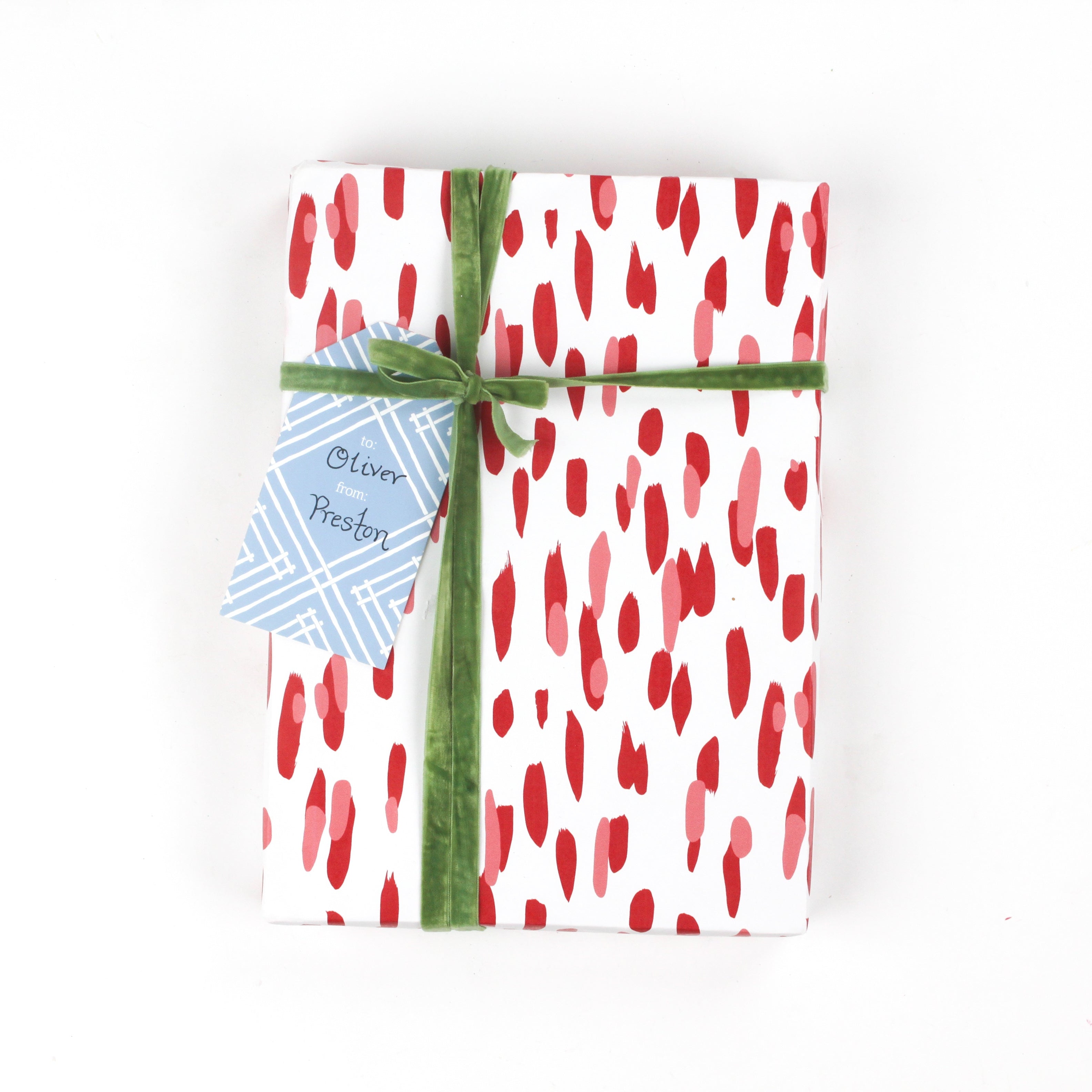 Front view of gift wrapped in red brushstroke wrapping paper with green ribbon and blue gift tag.