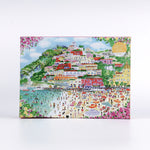 Coast of Italy 1000-piece puzzle by Michael Storrings featuring a colorful illustrated coastal village with hillside houses, beach umbrellas, swimmers, and vibrant Mediterranean scenery on the front of the puzzle box.