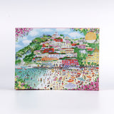 Coast of Italy 1000-piece puzzle by Michael Storrings featuring a colorful illustrated coastal village with hillside houses, beach umbrellas, swimmers, and vibrant Mediterranean scenery on the front of the puzzle box.