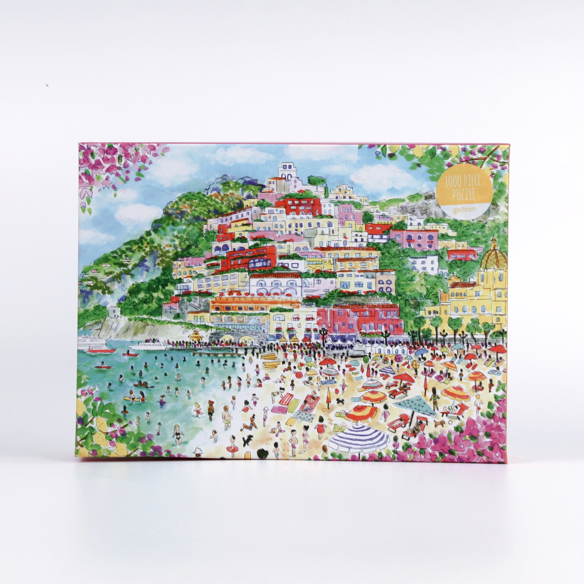 Coast of Italy 1000-piece puzzle by Michael Storrings featuring a colorful illustrated coastal village with hillside houses, beach umbrellas, swimmers, and vibrant Mediterranean scenery on the front of the puzzle box.