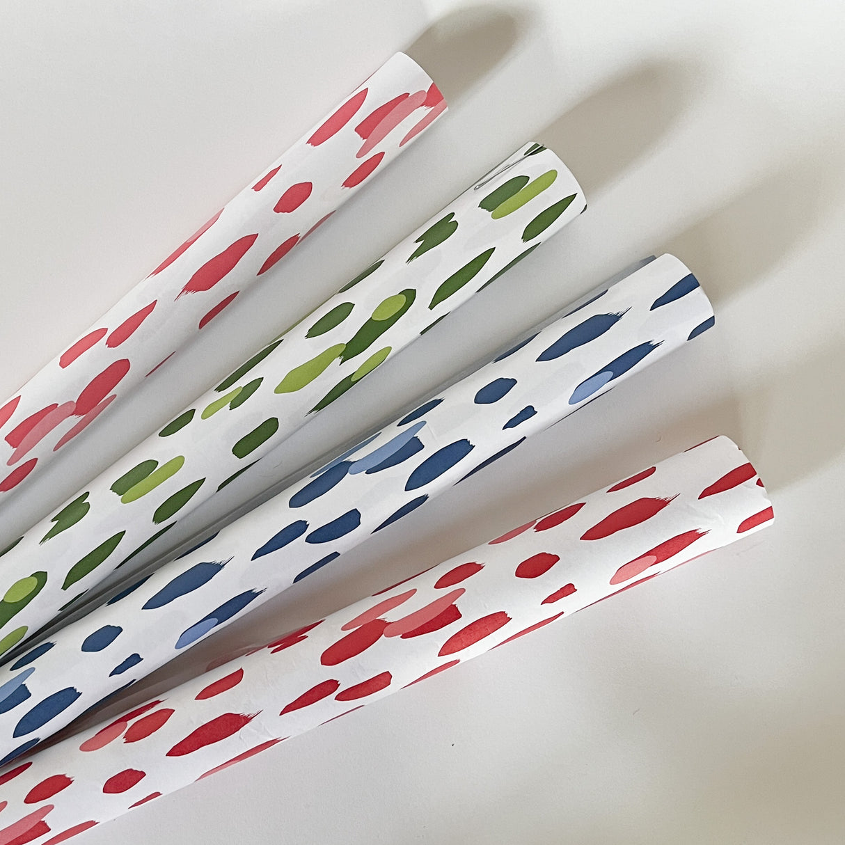 four paper table runners in pink, green, blue and red featuring a brushtroke  pattern by madcap cottage