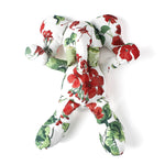 White stuffed elephant toy with red and green floral pattern and green bow.