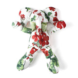 White stuffed elephant toy with red and green floral pattern and green bow.