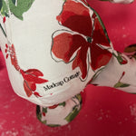 White stuffed elephant toy with red and green floral pattern and green bow close-up.