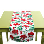 Red and green floral table runner displayed on a green table.