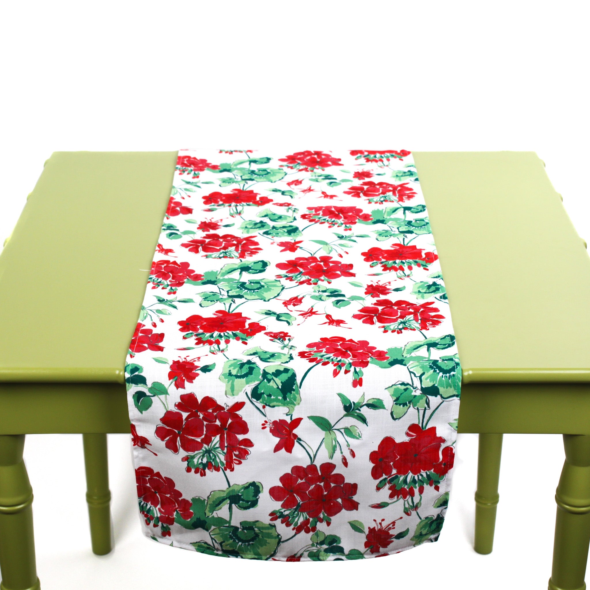 Red and green floral table runner displayed on a green table.
