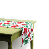 Side view of a red and green floral table runner draped over a green table.