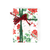 Front view of gift wrapped in red geranium wrapping paper with green and red ribbon.