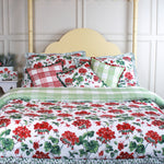 a bed covered with geranium print bedding on a yellow canopy best against a white panelled wall. 