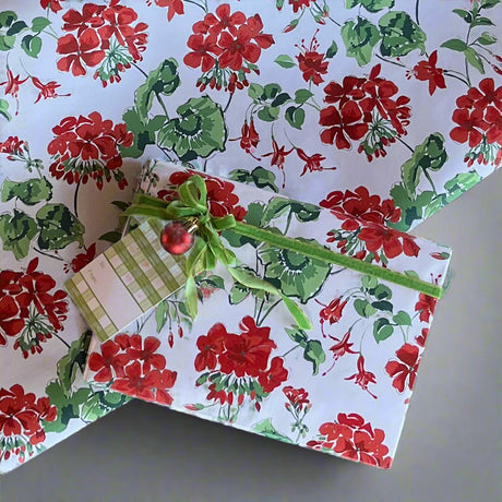 A gift wrapped with geranium wrapping paper and a green ribbon bow with the wrapping paper in the background to see the full pattern.