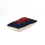 Red and blue crab throw pillow side view with navy textured fabric and beige backing.