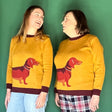 two women wearing mustard color sweaters with a large dachshund motif