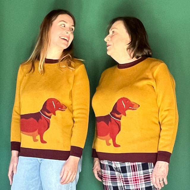 two women wearing mustard color sweaters with a large dachshund motif