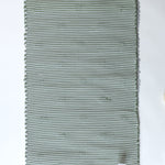 the reverse side of A rectangular green accent rug with small daisy shaped accents scattered across it. 