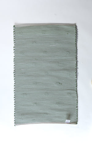 the reverse side of A rectangular green accent rug with small daisy shaped accents scattered across it. 
