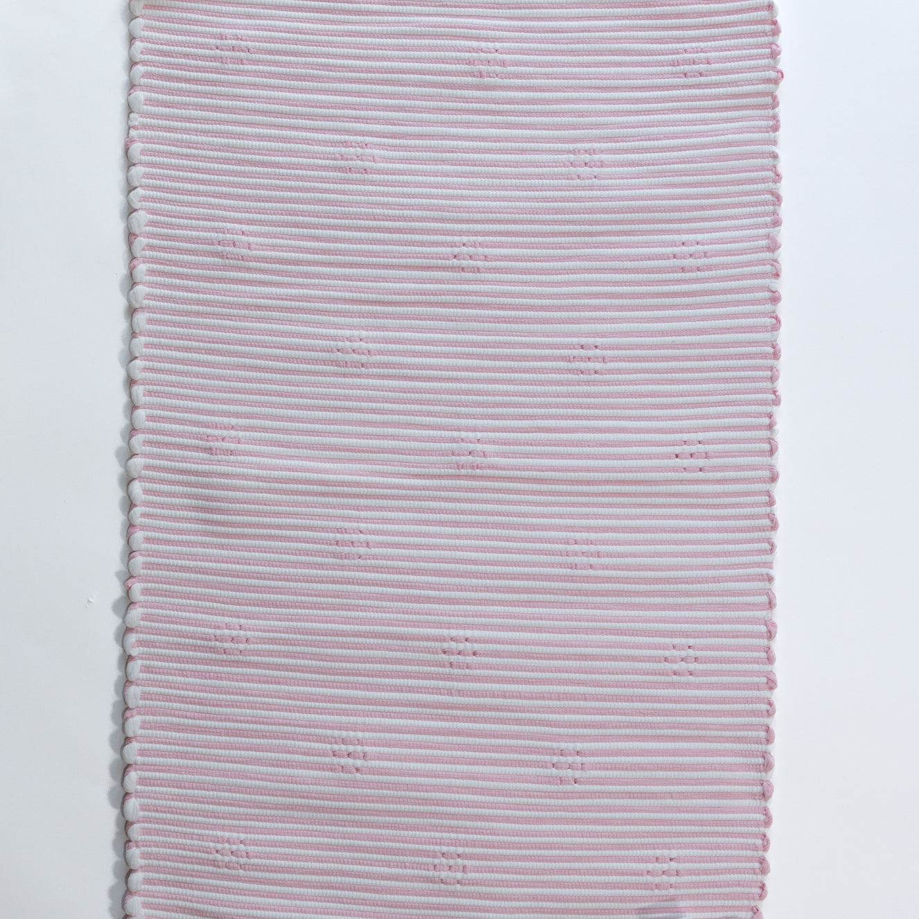 the plain reverse side of a pink accent rug