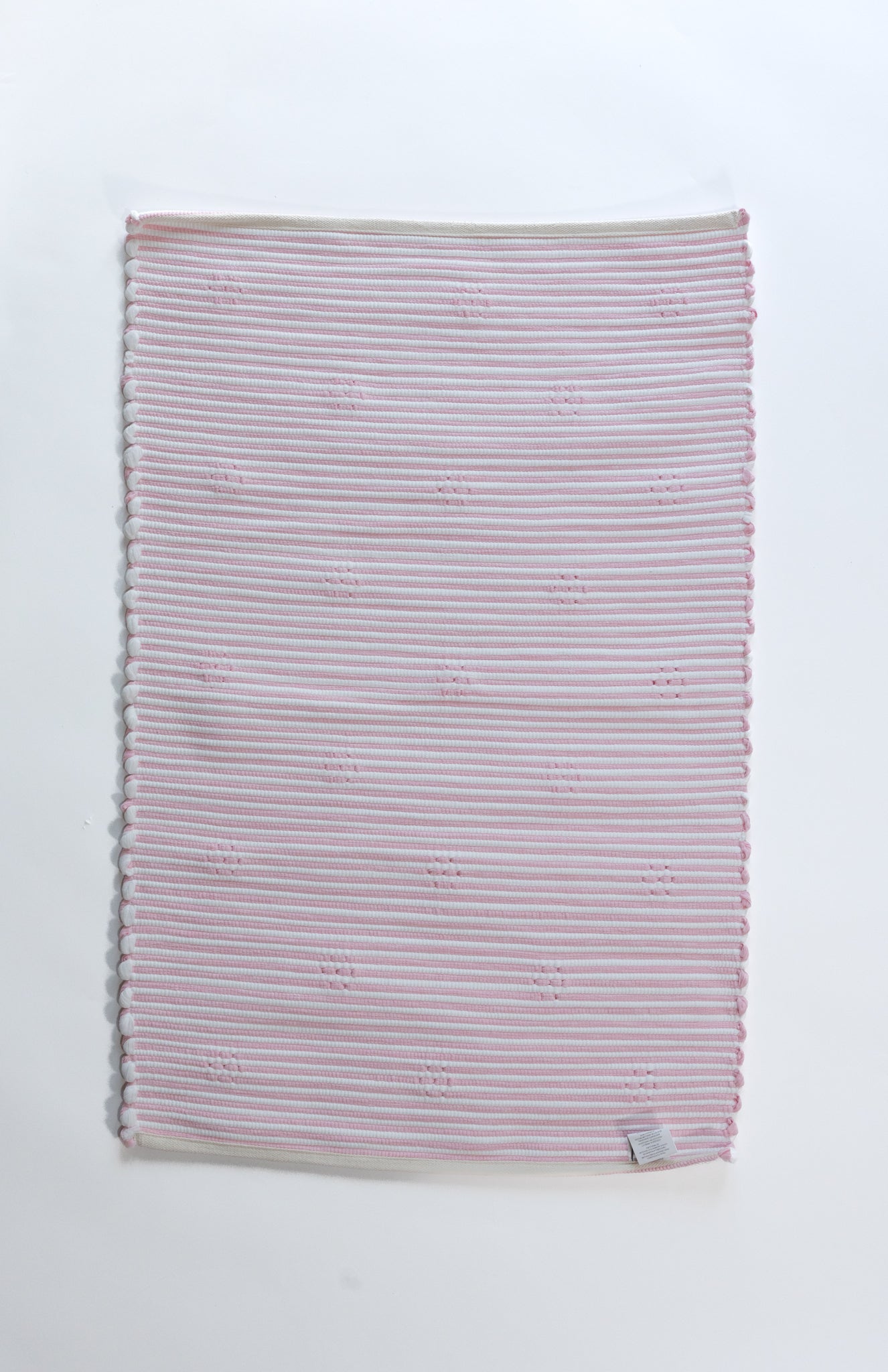 the plain reverse side of a pink accent rug