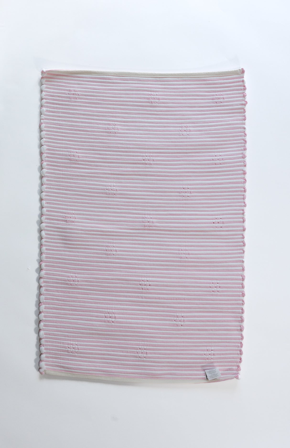 the plain reverse side of a pink accent rug