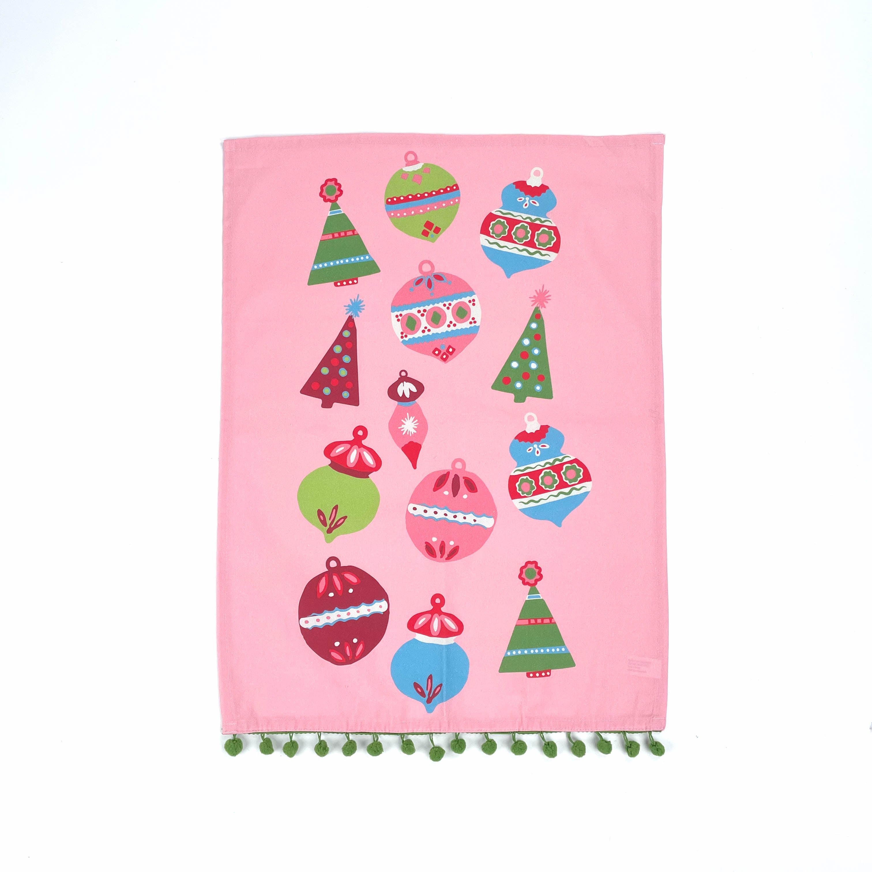 A pink christmas tea towel trimmed with green pom pom and colorful Christmas-themed decorations on a white background